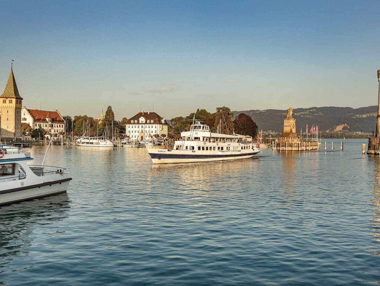 Starten Sie Ihre unvergessliche Schifffahrt vom historischen Lindauer Hafen. Genießen Sie die atemberaubenden Ausblicke auf den Bodensee und die Alpen, während Sie entspannen und die Schönheit der umliegenden Natur bewundern. Lindauer Hafen_Schiffahrt