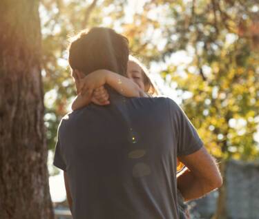 Ein Vater trägt sein Kind liebevoll im Arm und umarmt es sanft, während sie einen Moment der Nähe und Geborgenheit teilen – ein Zeichen der unendlichen Liebe und Verbundenheit Vater und Kind