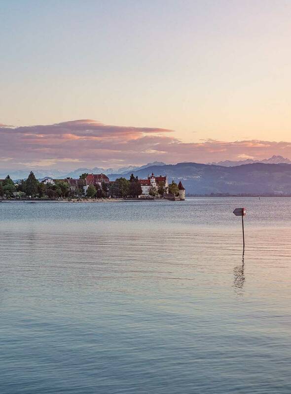 Der Bodensee bei Sonnenaufgang ist ein magischer Anblick: Das erste Licht des Tages taucht das Wasser in sanfte Farben, während die Berge im Hintergrund in warmes Licht getaucht werden – ein friedlicher Moment der Ruhe und Schönheit Bodensee Sonnenaufgang